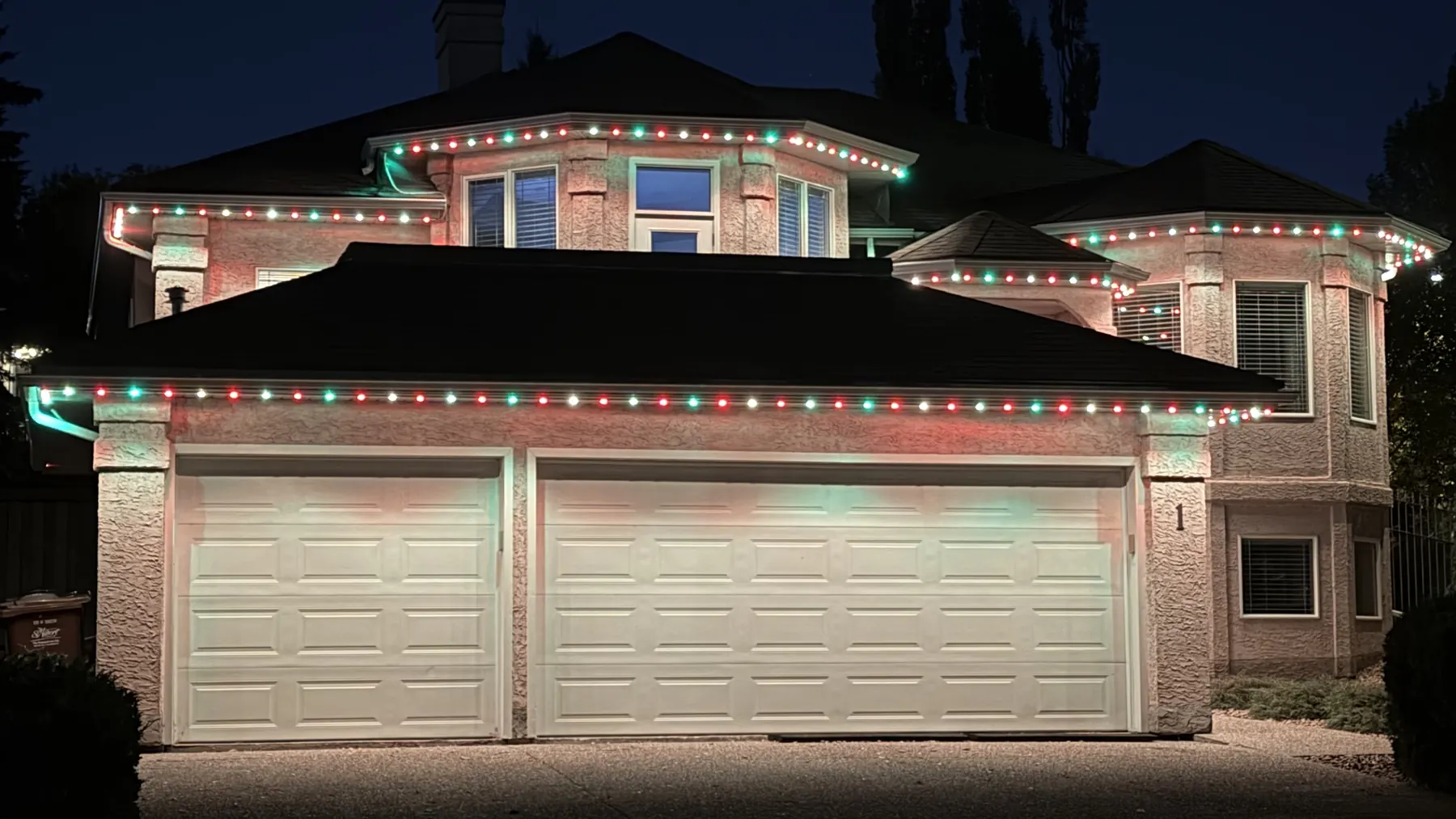Red, green, and white permanent outdoor lights outlining a Nanaimo home at night