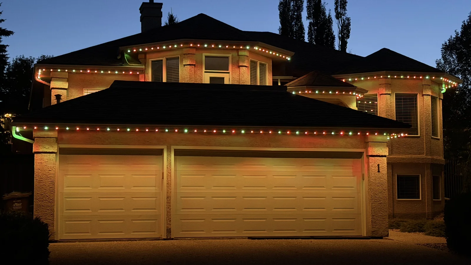 Red, green and warm-white roofline lighting on a home at dusk