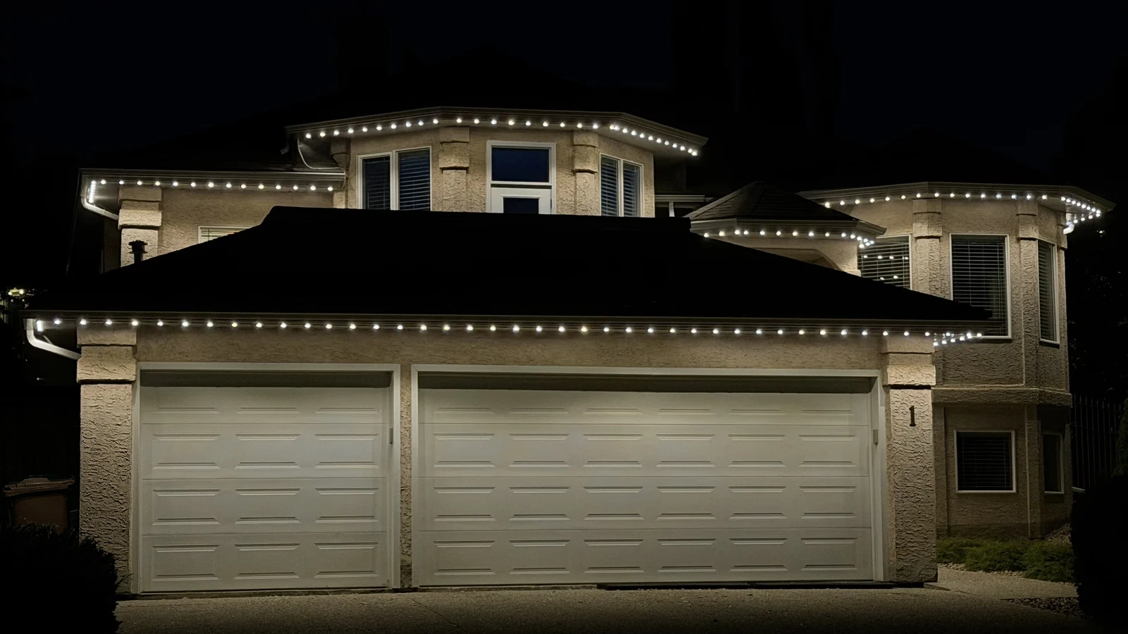 Warm-white permanent lighting across the roofline of a two-storey home