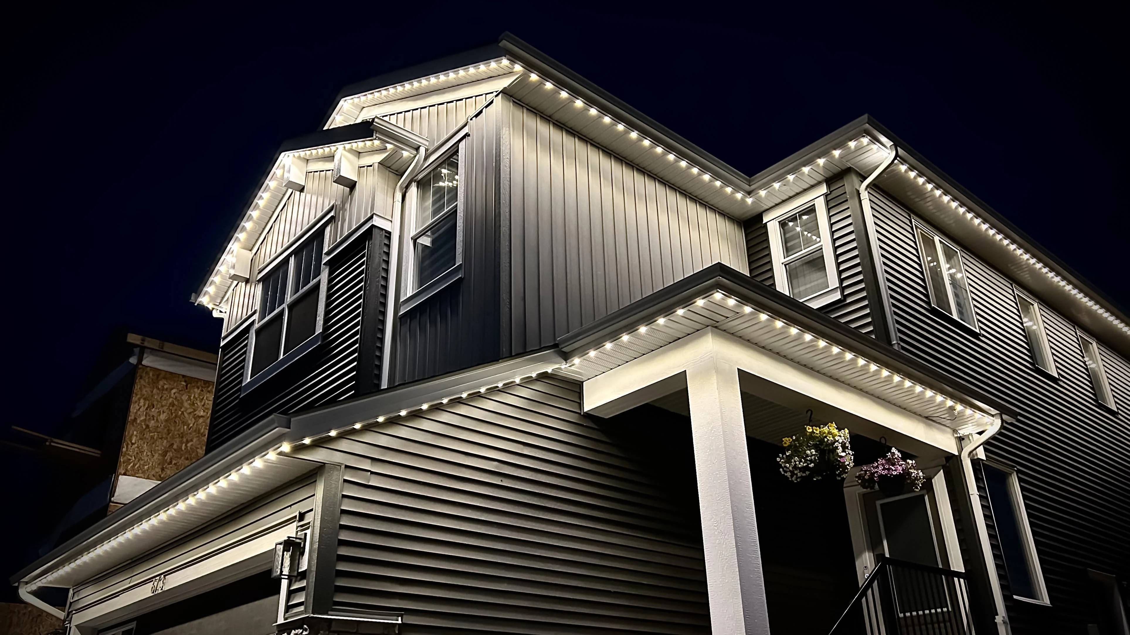 Warm-white permanent lighting outlining a modern two-storey Nanaimo home