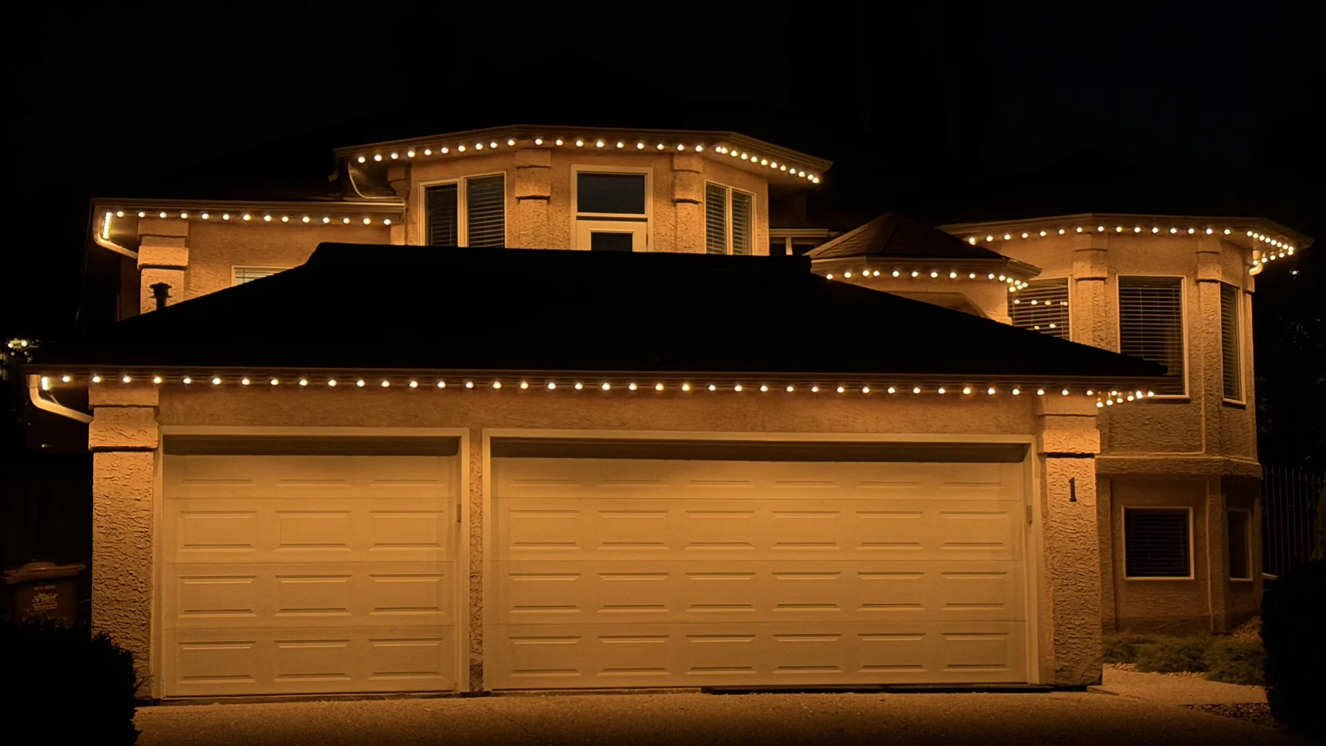 Warm amber LED pixels outlining the eaves and garage roofline of a Nanaimo home at night
