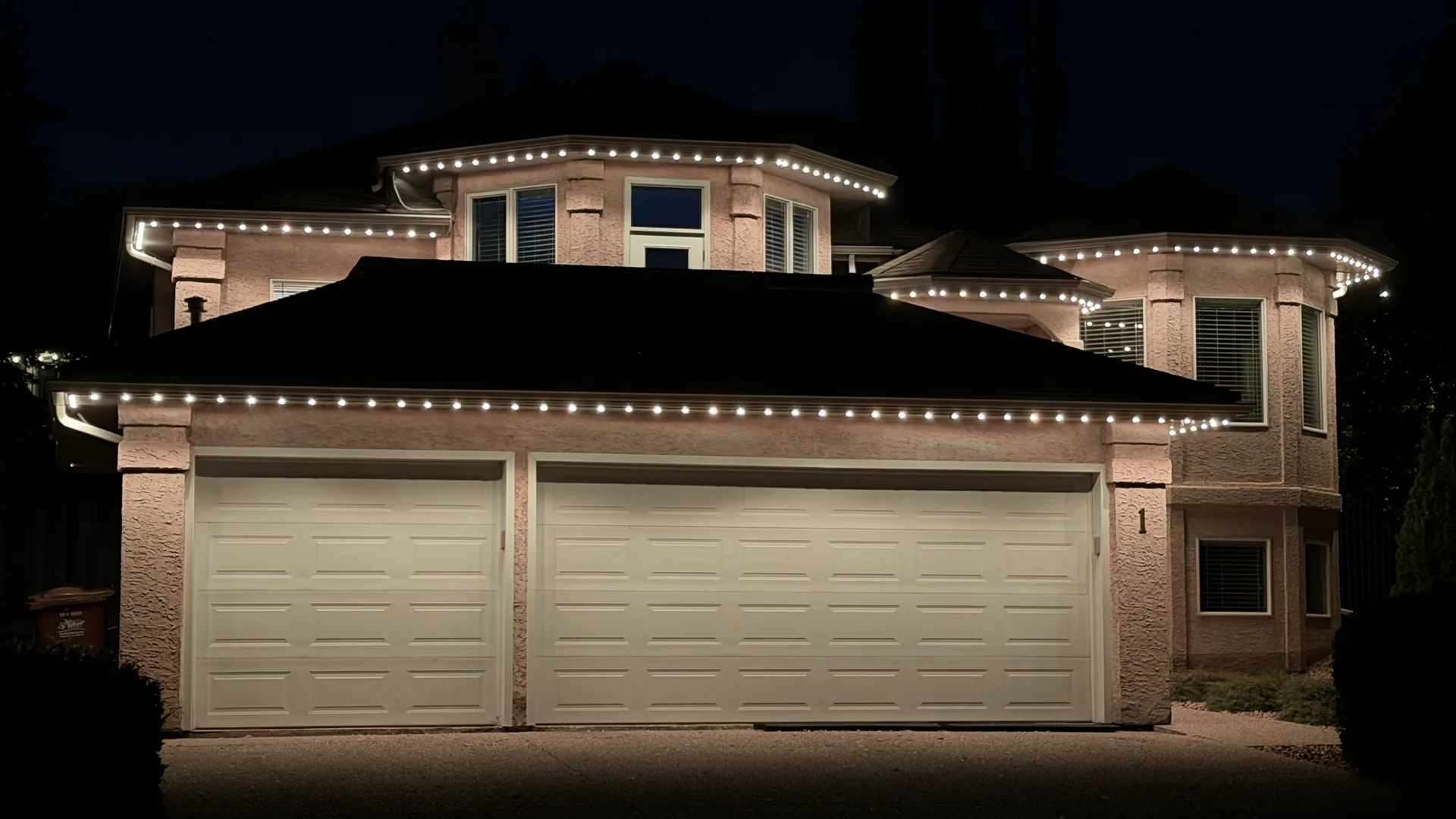 Dedicated warm-white LED soffit lights illuminating the roofline and garage of a home at night