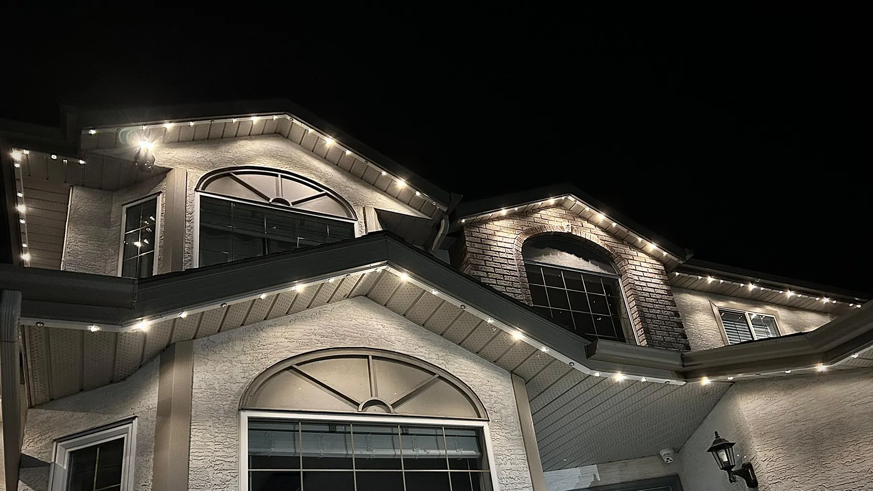 Warm-white permanent outdoor lights outlining the soffits and rooflines of a two-storey home at night